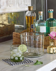 Alcohol bottles, glass vase with 14k gold leaf design and glasses on a kitchen counter with a decorative touch.