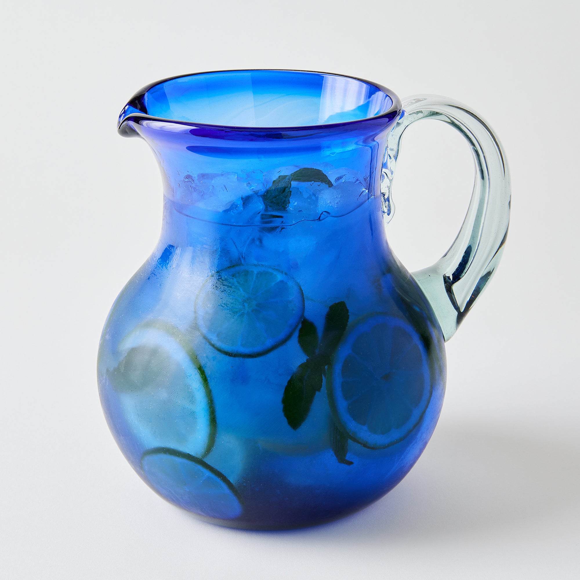 Blue glass pitcher with clear handle filled with drinks