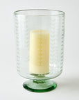 Clear glass candle holder with a clear base containing a white candle on a white background