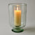 Decorative glass candle holder with a lit candle on a plain background