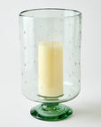 Clear glass candle holder with a clear base containing a white candle on a white background