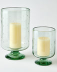 Two clear glass candle holders with candles on a white background