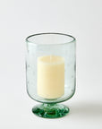 Clear glass candle holder with a white candle on a white background