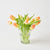 Clear glass vase with peach-colored tulips on a white background