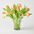 Clear glass vase with peach-colored tulips on a white background