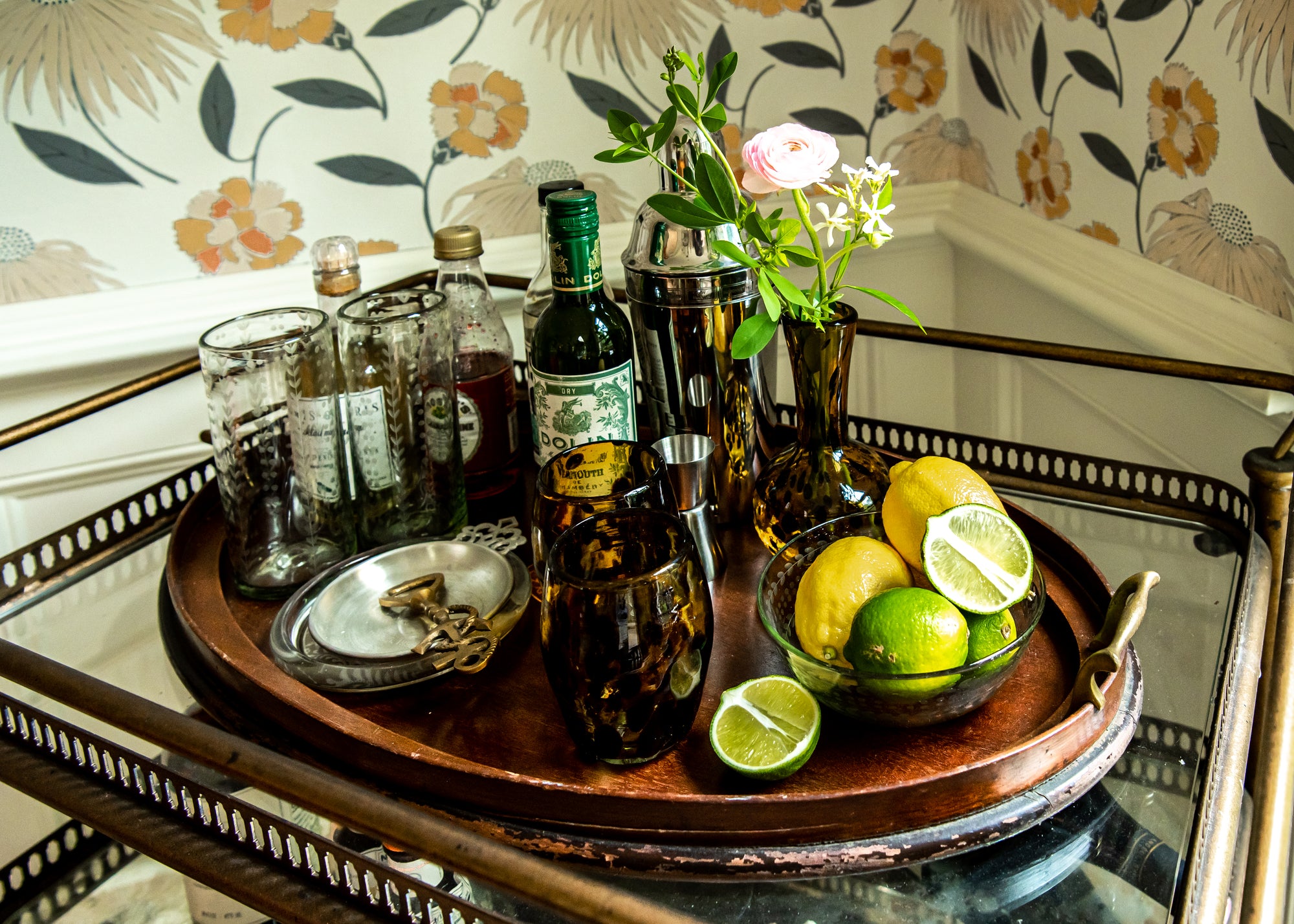 Bar cart with drinks and garnishes on a decorative wall background