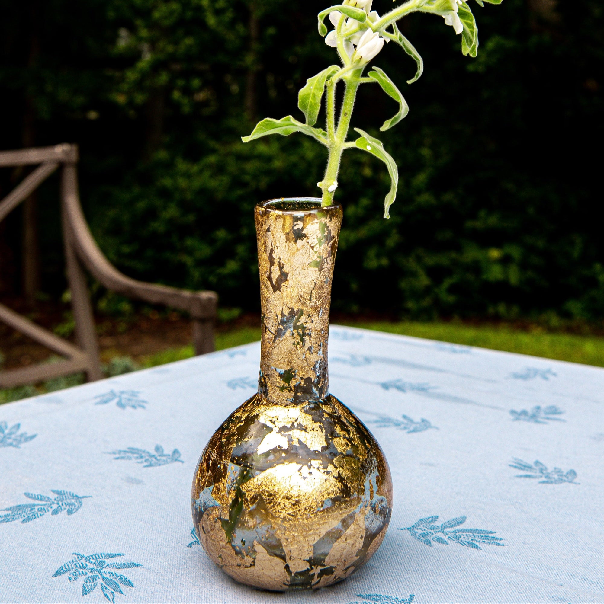 Gold decorative vase with a plant on a table outdoors