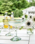 Outdoor setting with cocktails, limes, and flowers on a table.