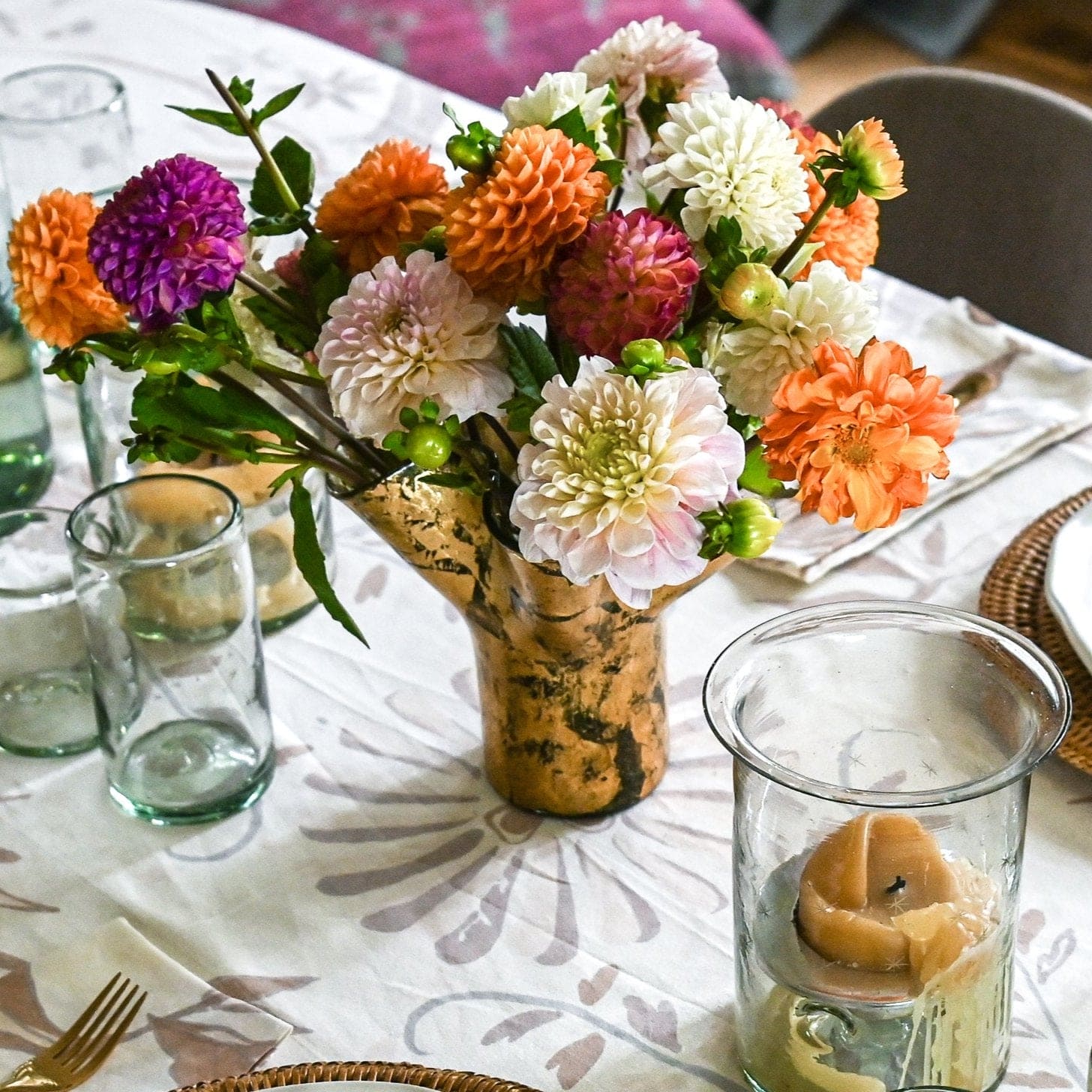 Clear vase covered in 14k gold leaf on a table together with other tablewares