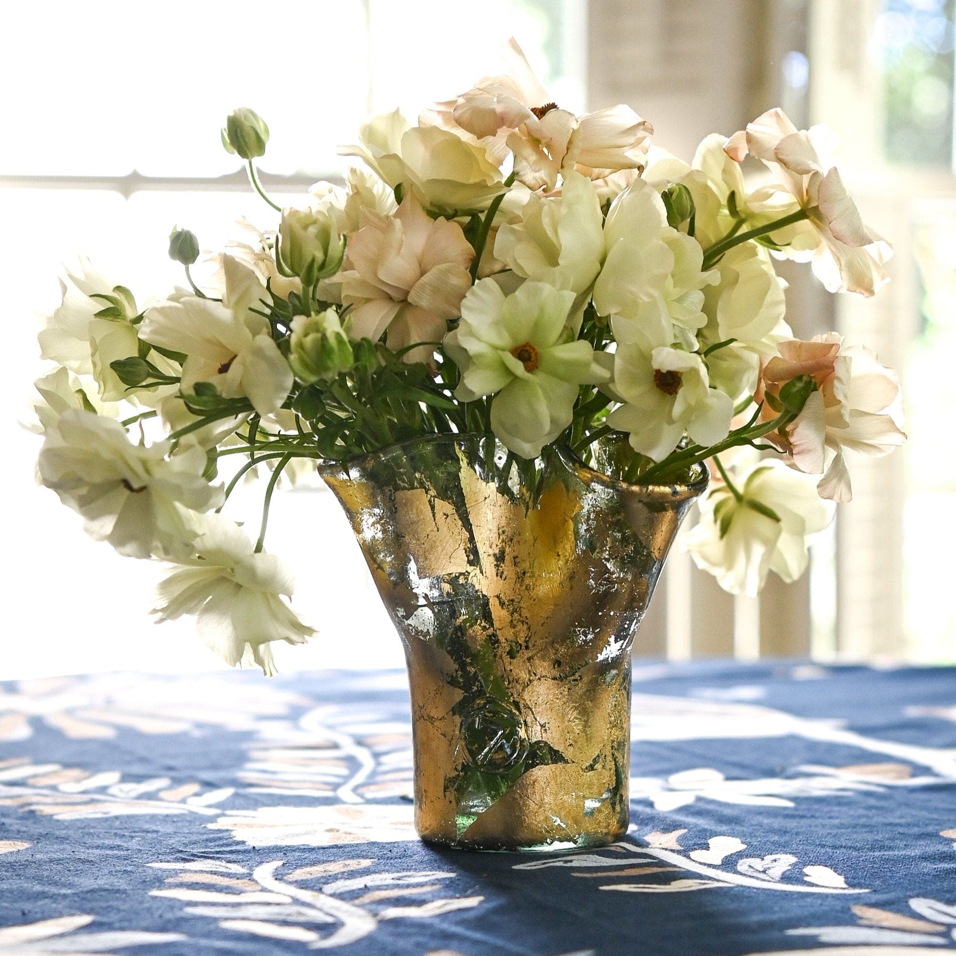 A clear glass vase covered in hand-applied 14k gold leaf with flowers