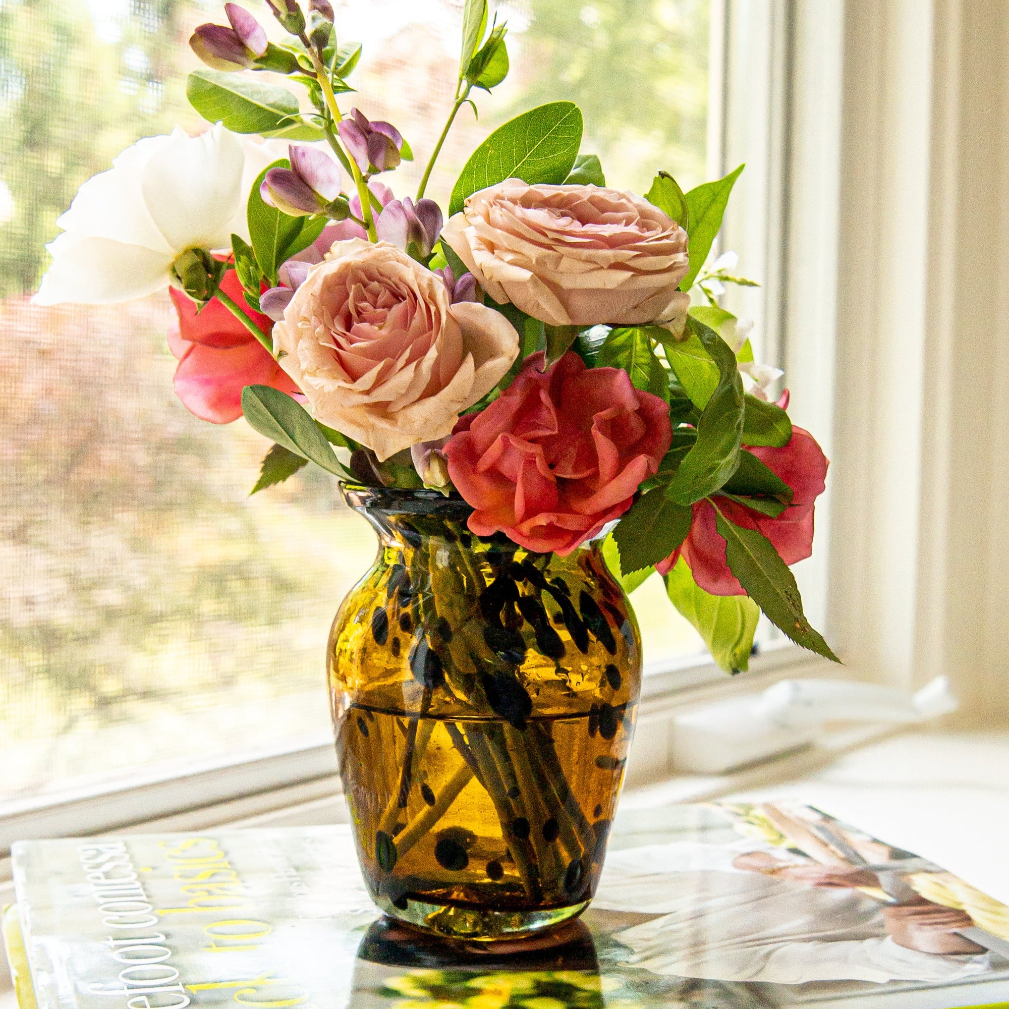 Vase with pink and red flowers on a table by a window