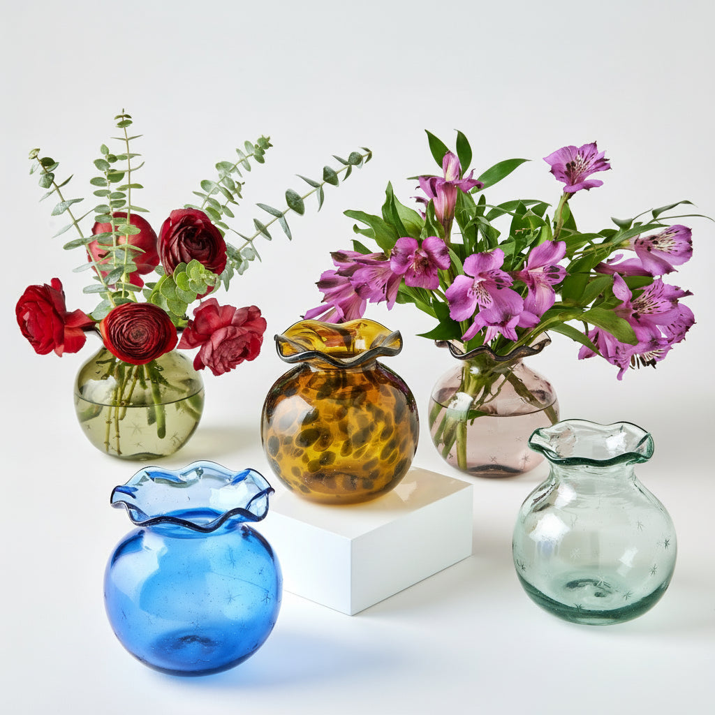 Collection of colorful glass vases with flowers on a white background