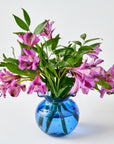 Blue glass vase with pink flowers on a white background