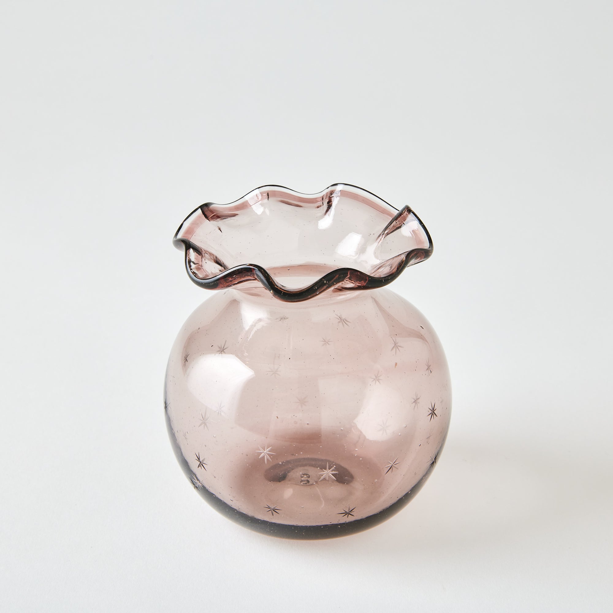 Pink glass vase with wavy rim on a white background