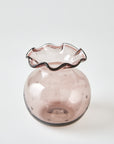 Pink glass vase with wavy rim on a white background