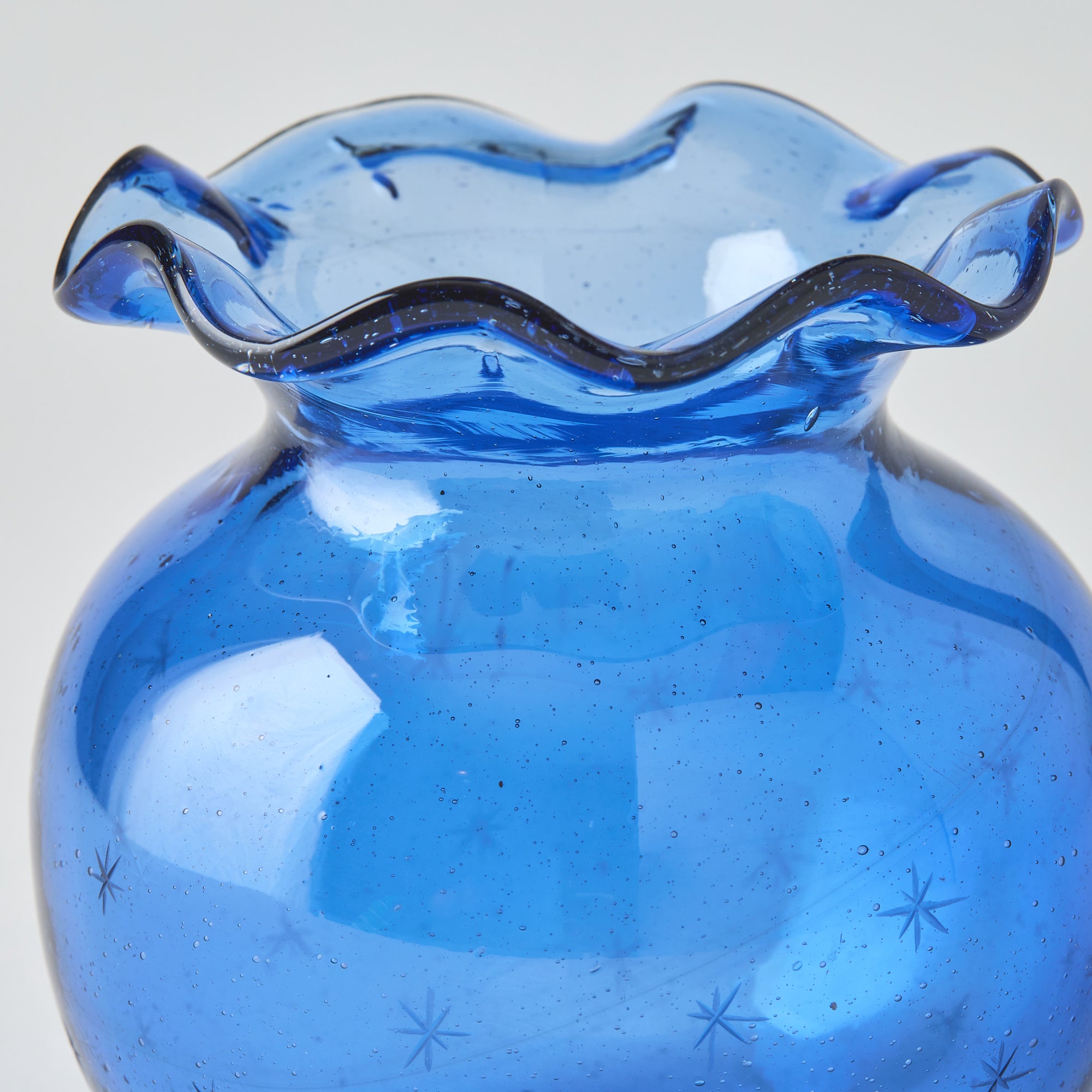 Blue glass vase with wavy rim on a white background
