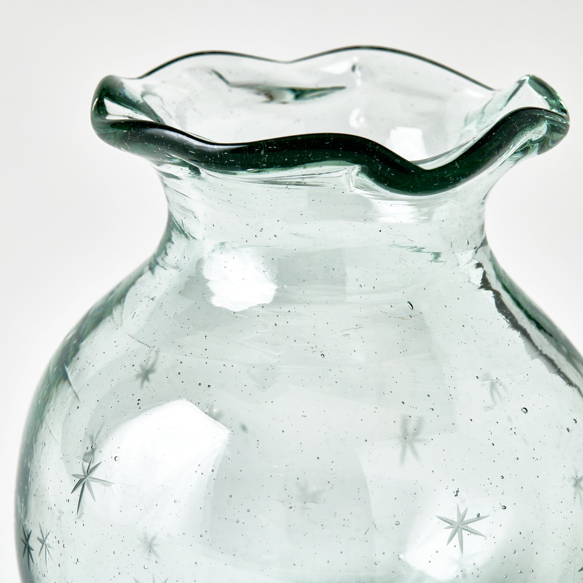 Clear starry glass vase with wavy rim on a white background