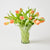 Clear glass vase with peach-colored tulips on a light gray background