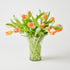 Clear glass vase with peach-colored tulips on a light gray background