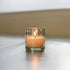A clear glass votive with hand-etched stars on it, reflecting light.