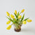 Pink glass vase with yellow tulips on a light gray background