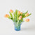 Bouquet of peach-colored tulips in a blue glass vase on a light background