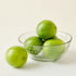 Green limes in a glass bowl on a white background