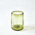 Green glass tumbler with textured surface on a white background