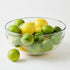 Clear glass bowl filled with lemons and limes on a white background