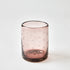 Pink glass tumbler with star patterns on a white background