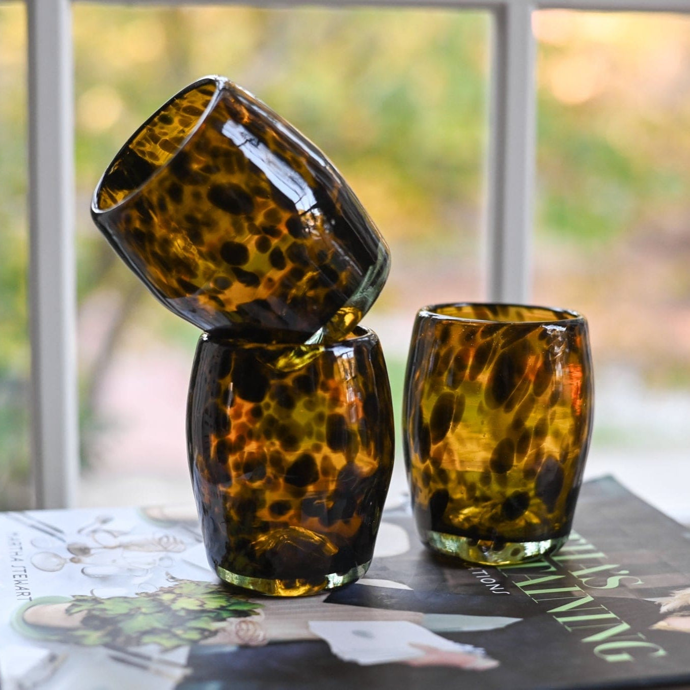 Three tortoiseshell patterned glasses on a surface with a blurred outdoor background