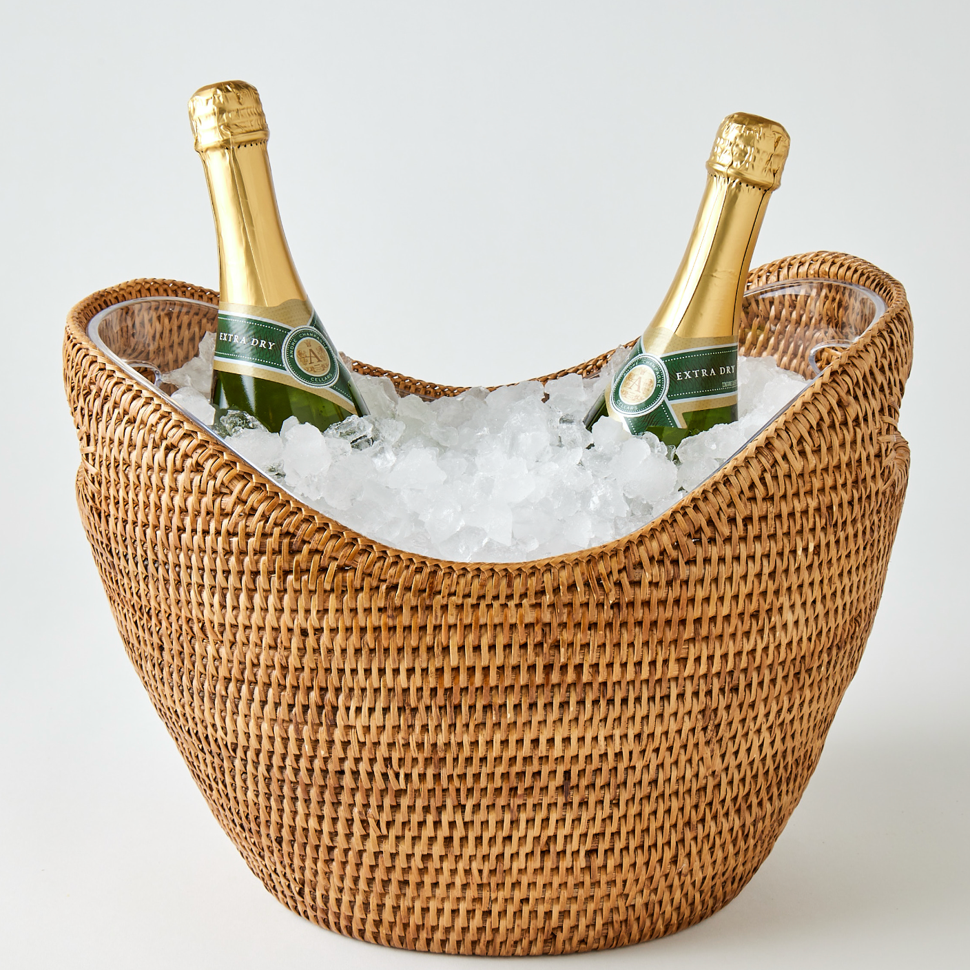Two bottles of champagne in a woven ice bucket on a light background