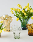 Collection of glass vases with yellow tulips on a white background