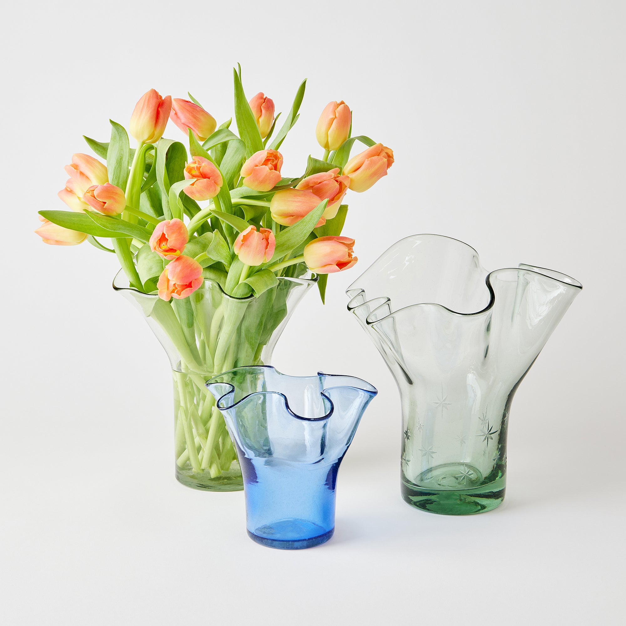 Three glass vases with a bouquet of tulips on a white background